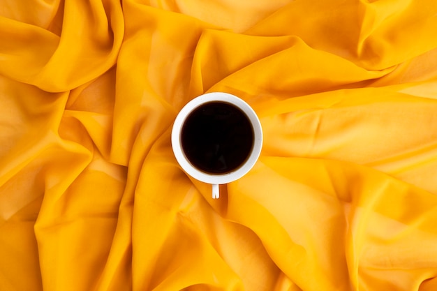 Concept minimaliste. Café sur fond d'écharpe jaune. Automne, concept d'automne. Mise à plat, vue de dessus, espace de copie