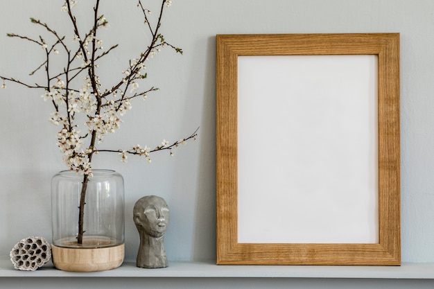 Concept minimaliste sur l'étagère avec cadre photo marron, fleur dans un vase, sculpture et accessoires personnels élégants dans un intérieur élégant.