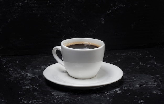 Photo un concept minimaliste d'une tasse de café et qui se dresse sur un fond abstrait noir.