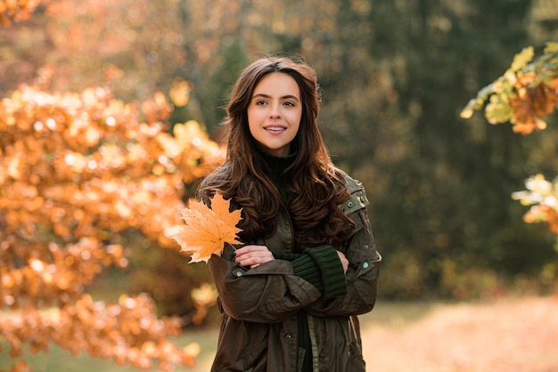 Concept de mode automne fille élégante dans un style automnal posant sur fond de feuille d'érable rouge à l'extérieur un