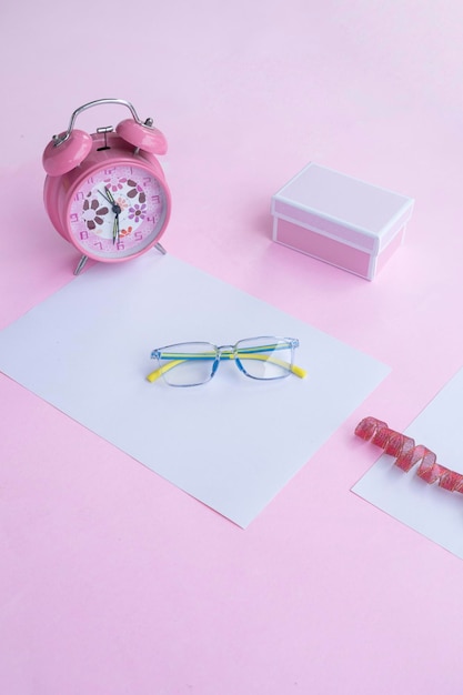 Concept de mode et de beauté à plat avec des accessoires pour femmes lunettes carrées sur fond rose