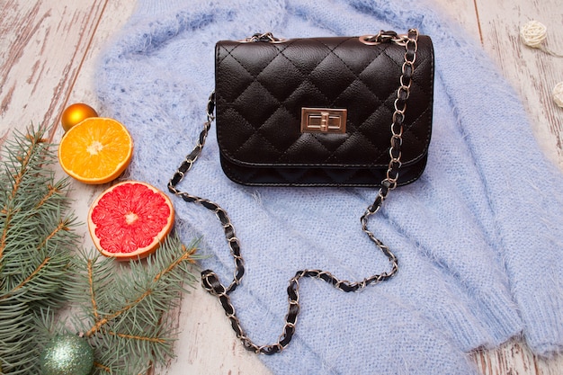 Concept de mode Sac femme noir sur pull, branche épinette et orange