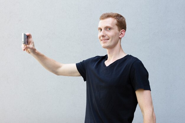 Concept de mode, de style, d'émotions et de personnes - Portrait en gros plan d'une rousse d'un beau mec viril avec des taches de rousseur. L'heure du selfie, la blogueuse fait une photo pour sa page de réseaux sociaux.