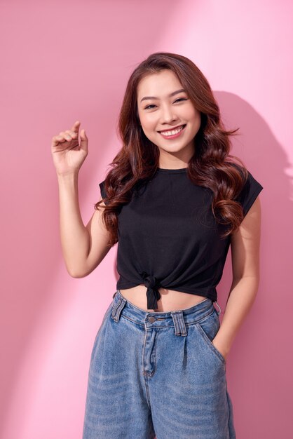 Concept de mode de vie, de beauté et de personnes: jeune fille souriante mignonne sur mur rose