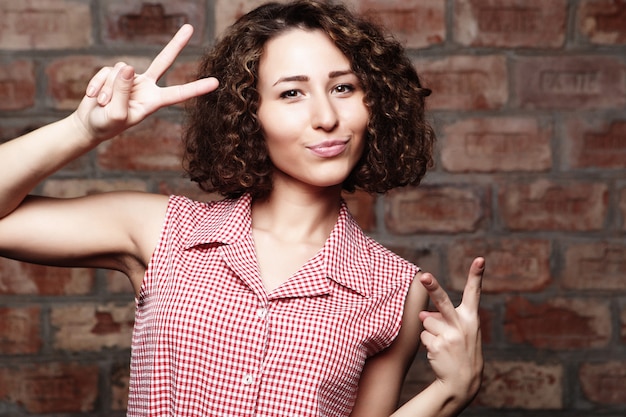 Concept de mode de vie et les gens: belle femme montrant la victoire ou p