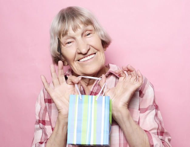 Concept de mode de vie et de personnes Happy senior woman with shopping bag sur fond rose