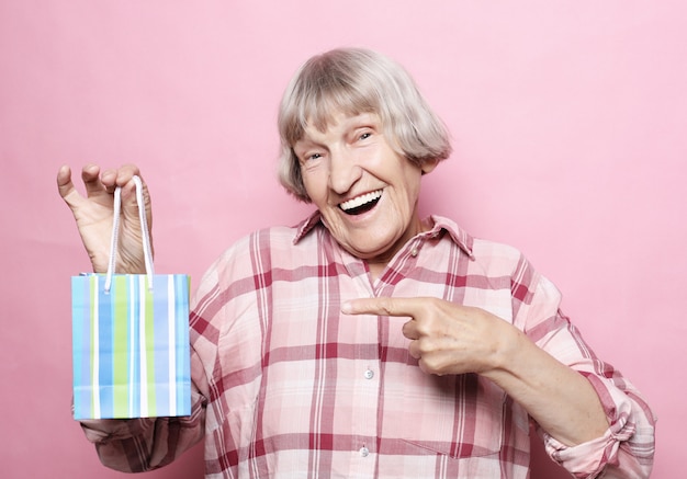 Concept de mode de vie et de personnes. Heureuse femme senior avec sac à provisions sur rose