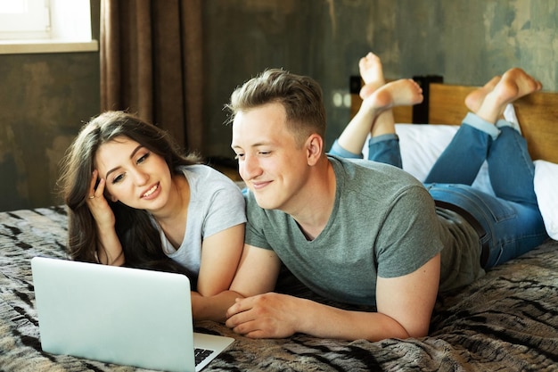 Concept de mode de vie et de personnes Jeune couple marié allongé sur le lit à la maison et utilisant un ordinateur portable