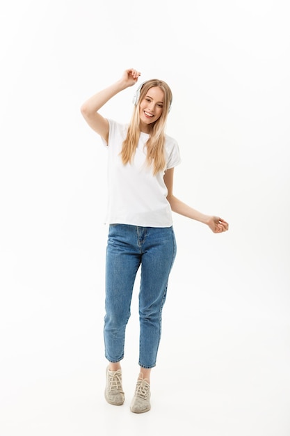 Photo concept de mode de vie : portrait d'une étudiante joyeuse et heureuse écoutant de la musique avec des écouteurs tout en dansant isolée sur fond blanc