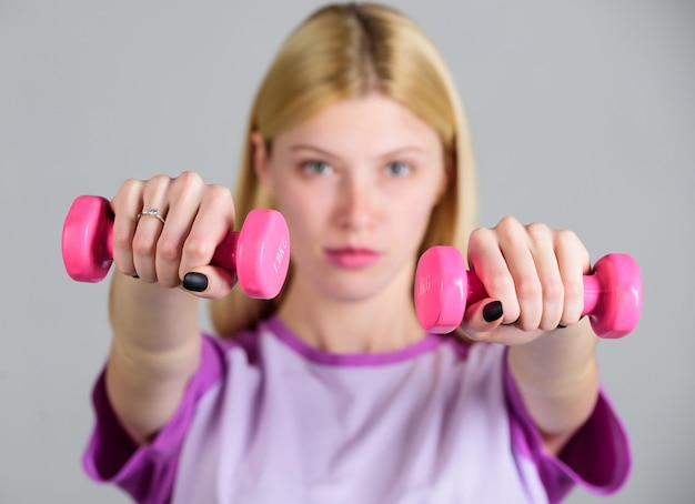 Concept de mode de vie sain Entraîneur de fitness femme exerçant avec des haltères Exercices faciles avec des haltères Entraînement avec des haltères Fille tenir des haltères Exercices de biceps pour femme