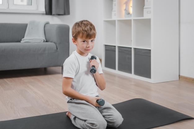 concept de mode de vie sain pour enfants Portrait d'un garçon enfant caucasien exerçant avec des haltères