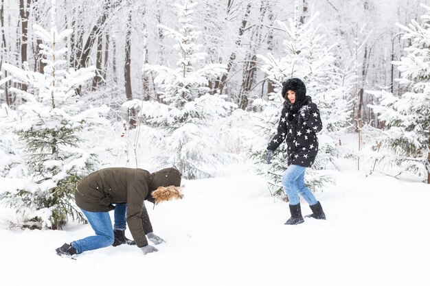 Photo concept de mode de vie, de saison et de loisirs - couple amusant jouant à la boule de neige dans le parc d'hiver.