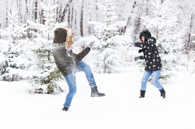 Concept de mode de vie, de saison et de loisirs - Couple amusant jouant à la boule de neige dans le parc d'hiver.