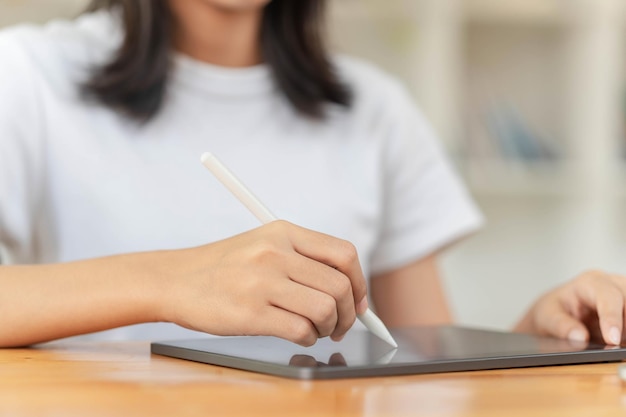 Concept de mode de vie et de technologie Jeune femme asiatique écrivant sur une tablette pour travailler en ligne à la maison