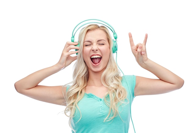 concept de musique, de technologie et de personnes - jeune femme ou adolescente heureuse avec un casque chantant une chanson et montrant un geste rock