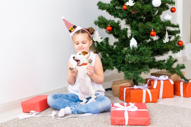 Concept de Noël, d'animaux et de vacances - Enfant en bonnet de Noel avec un chiot jack russell terrier.
