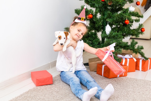 Concept de Noël, d'animaux et de vacances - Enfant en bonnet de Noel avec un chiot jack russell terrier.