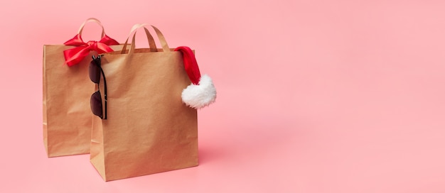 Concept de Noël, deux sacs en papier, des remises sur les accessoires, sur fond rose, bannière