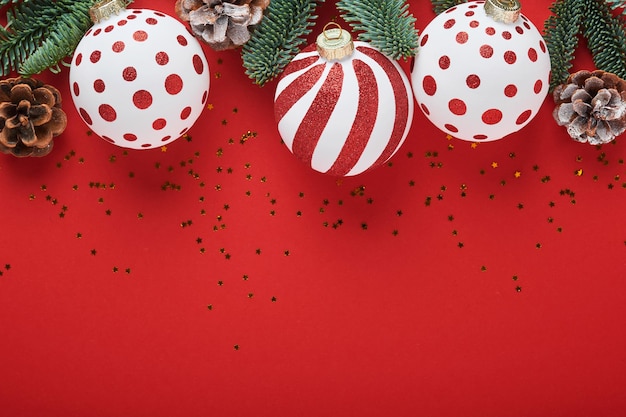Concept de Noël ou du Nouvel An avec boule de boules blanches et rouges, coffret cadeau et champagne avec ruban décoré et branches de sapin sur fond rouge. Bonne année 2022. Maquette.