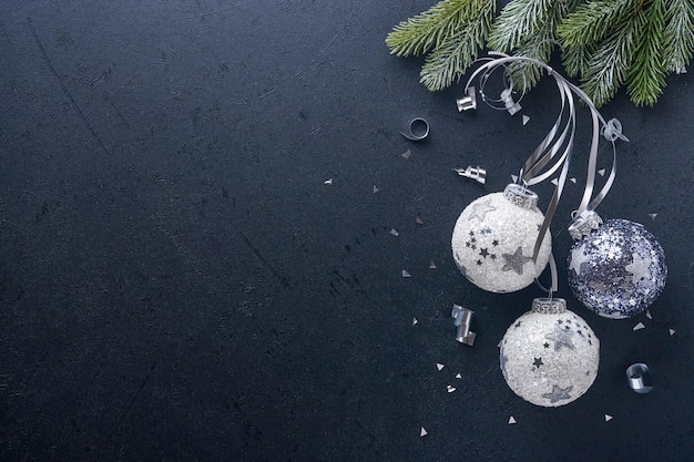 Concept de Noël ou du Nouvel An avec boule de boules noires et argentées, coffret cadeau et champagne avec ruban métallique argenté décoré sur fond noir. Bonne année 2022. Maquette.