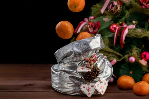 Concept de Noël et du nouvel an avec des mandarines volant dans un sac avec des cadeaux sur une table en bois