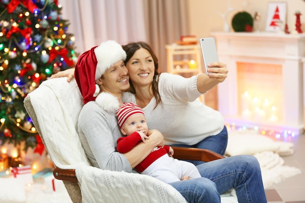 Concept de Noël : une famille heureuse prend un selfie dans une chambre décorée