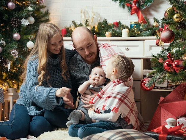 Concept de Noël famille souriante heureuse assis près de l'arbre