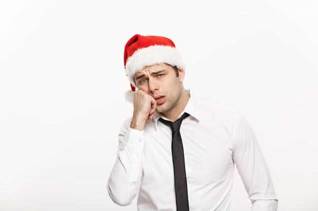Concept de Noël Handsome Business man wear santa hat posant avec une expression faciale stressante sur fond isolé blanc
