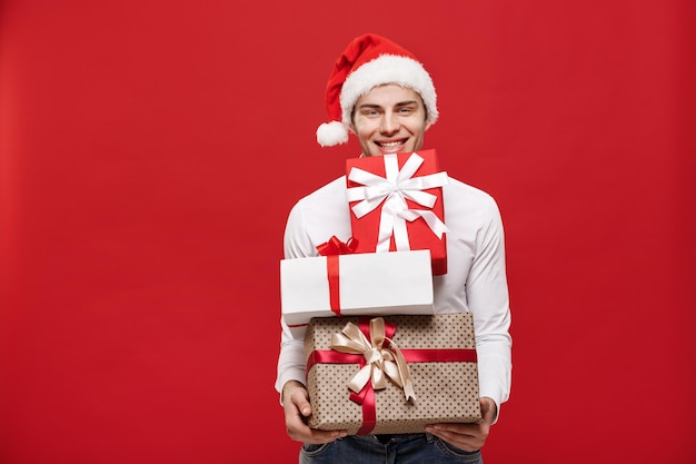 Concept de Noël Handsome caucasian happy businessman holding beaucoup de cadeaux avec porter santa hat posant sur fond isolé blanc