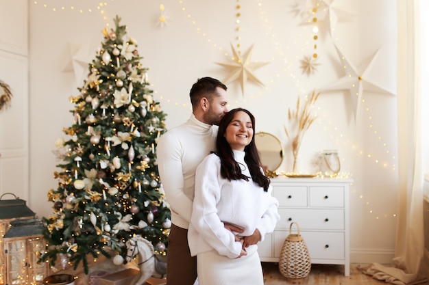 Concept de Noël heureux, couple amoureux étreindre et s'embrasser par l'arbre de Noël