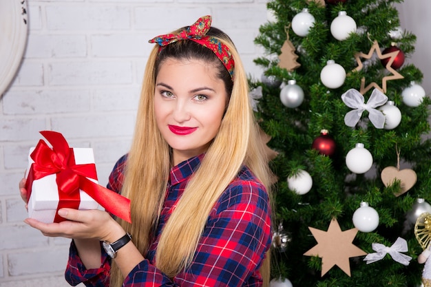 Concept de Noël - jeune femme avec boîte-cadeau et arbre de Noël décoré
