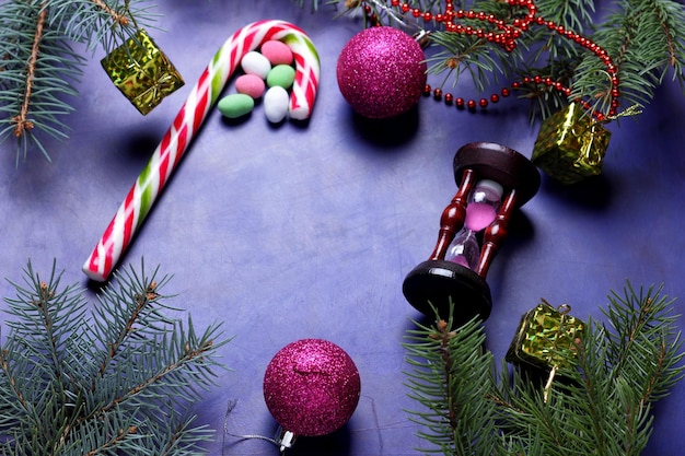 Concept de Noël jouets de Noël canne en bonbon sablier branches d'arbres de Noël sur fond violet gros plan