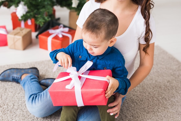 Concept de Noël, parent seul et vacances - Mignon petit garçon tenant un cadeau de Noël pour sa mère à la maison.