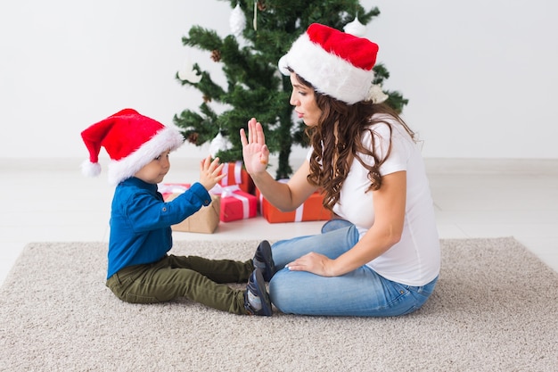 Concept de Noël, parent seul et vacances - Mignon petit garçon tenant un cadeau de Noël pour sa mère à la maison.