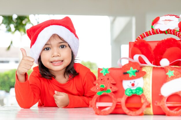 Concept de Noël, vacances et enfance - fille souriante avec boîte-cadeau à la maison