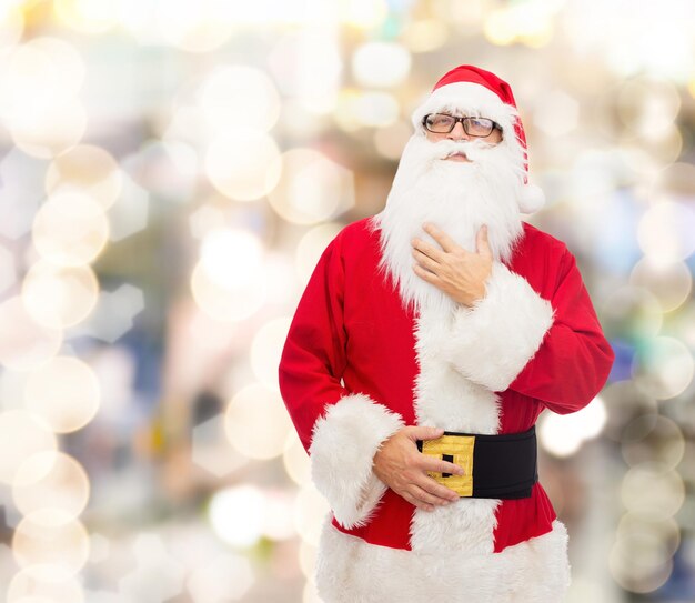 concept de noël, de vacances et de personnes - homme en costume de père noël sur fond de lumières bleues