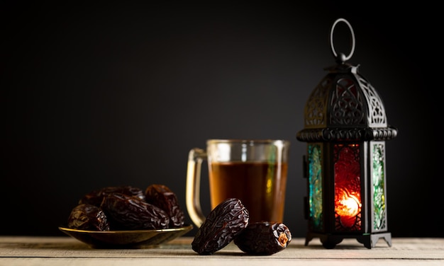 Concept de nourriture et de boissons du Ramadan Lanterne du Ramadan avec lampe arabe chapelet en bois thé dattes fruits et éclairage sur une table en bois avec un fond sombre