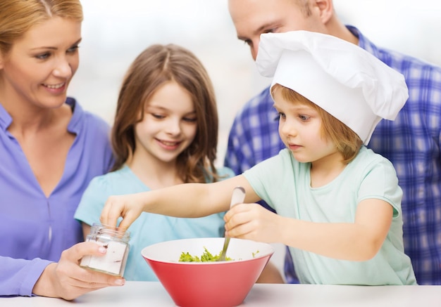 concept de nourriture, de famille, d'enfants, de bonheur et de personnes - famille heureuse avec deux enfants préparant le dîner à la maison