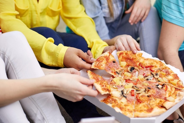 concept de nourriture, de loisirs et d'amitié - gros plan d'amis adolescents heureux mangeant de la pizza à la maison