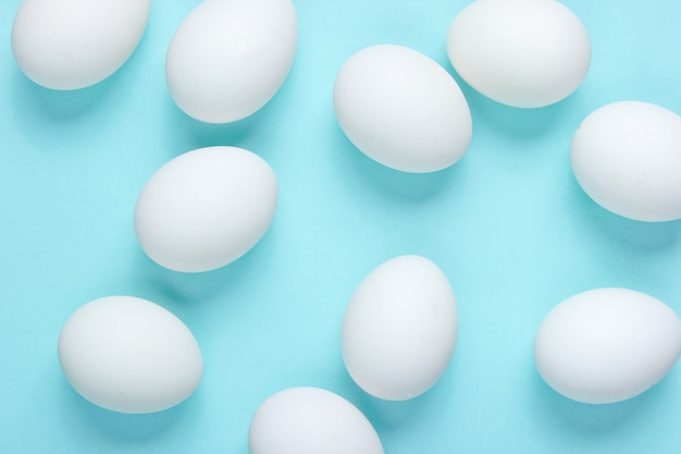 Concept de nourriture de minimalisme. Beaucoup d'oeufs sur une table bleue. Vue de dessus