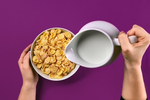 Concept de nourriture et de personnes mains de femme mangeant des céréales flocons de maïs pour le petit déjeuner et verser du lait