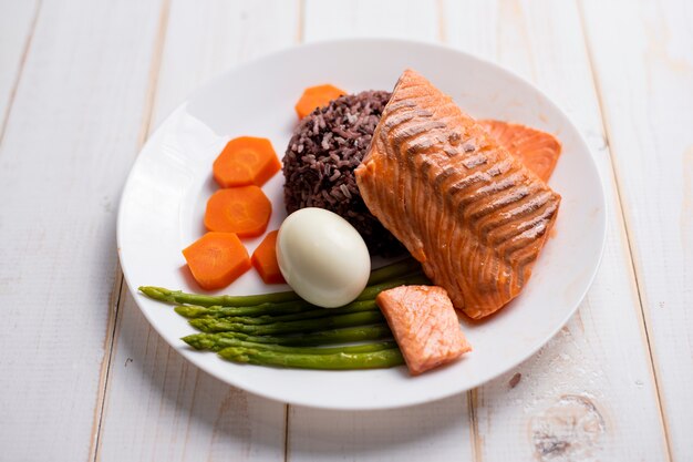 Concept de nourriture santé, saumon avec du riz et des légumes sur fond de bois