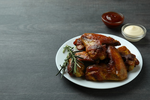 Concept de nourriture savoureuse avec des ailes de poulet cuit au four sur fond sombre, espace pour le texte