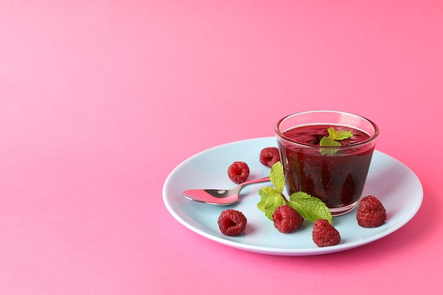 Concept de nourriture savoureuse avec de la confiture de framboises sur fond rose