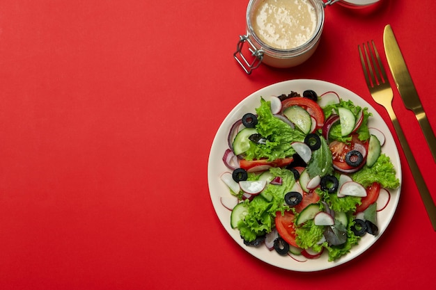 Concept de nourriture savoureuse avec salade de légumes à la sauce tahini sur fond rouge