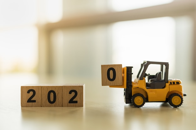 Concept De Nouvel An 2020. Close Up Of Toy Chariot élévateur Camion Machine Voiture Chargée Numéro 0 Bloc De Bois Jouet Sur Table Avec Copie Espace