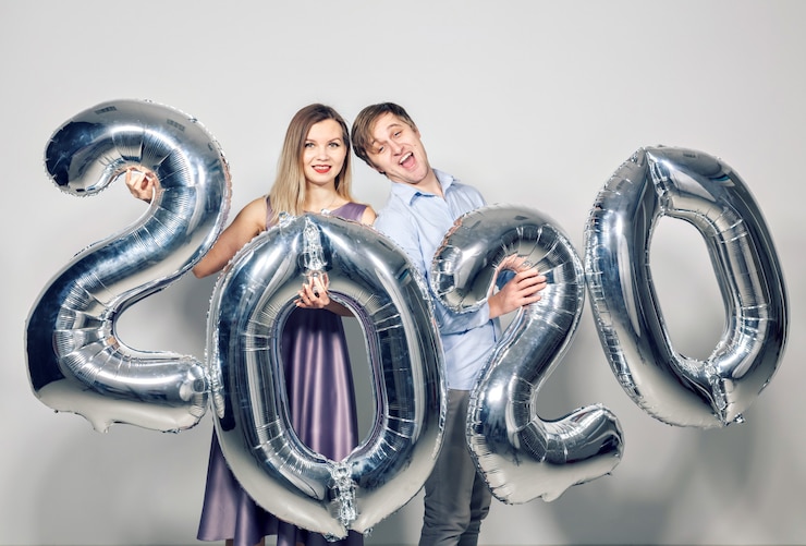 Photo concept de nouvel an, célébration et vacances - couple amoureux s'amuser avec signe 2020 en ballons d'argent pour le nouvel an