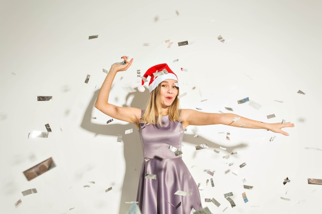 Concept de nouvel an et vacances - Heureuse jeune femme excitée en chapeau de père Noël dansant et riant sur fond blanc.