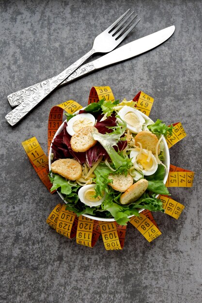 Le concept de nutrition diététique. Salade saine avec des œufs de caille et des feuilles vertes. Mètre ruban. Le concept de perte de poids grâce à la nutrition.