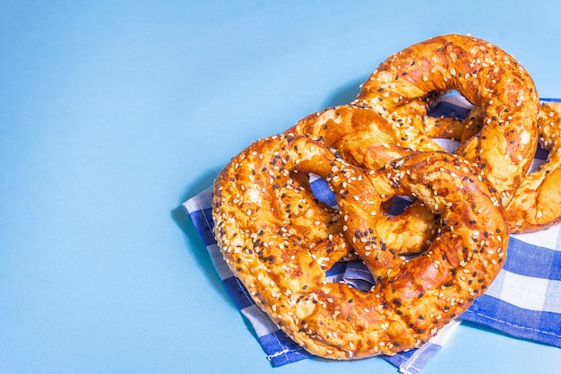 Concept d'Oktoberfest - bretzels sur une serviette traditionnelle. Lumière dure à la mode, ombre sombre. Fond bleu pastel, espace de copie